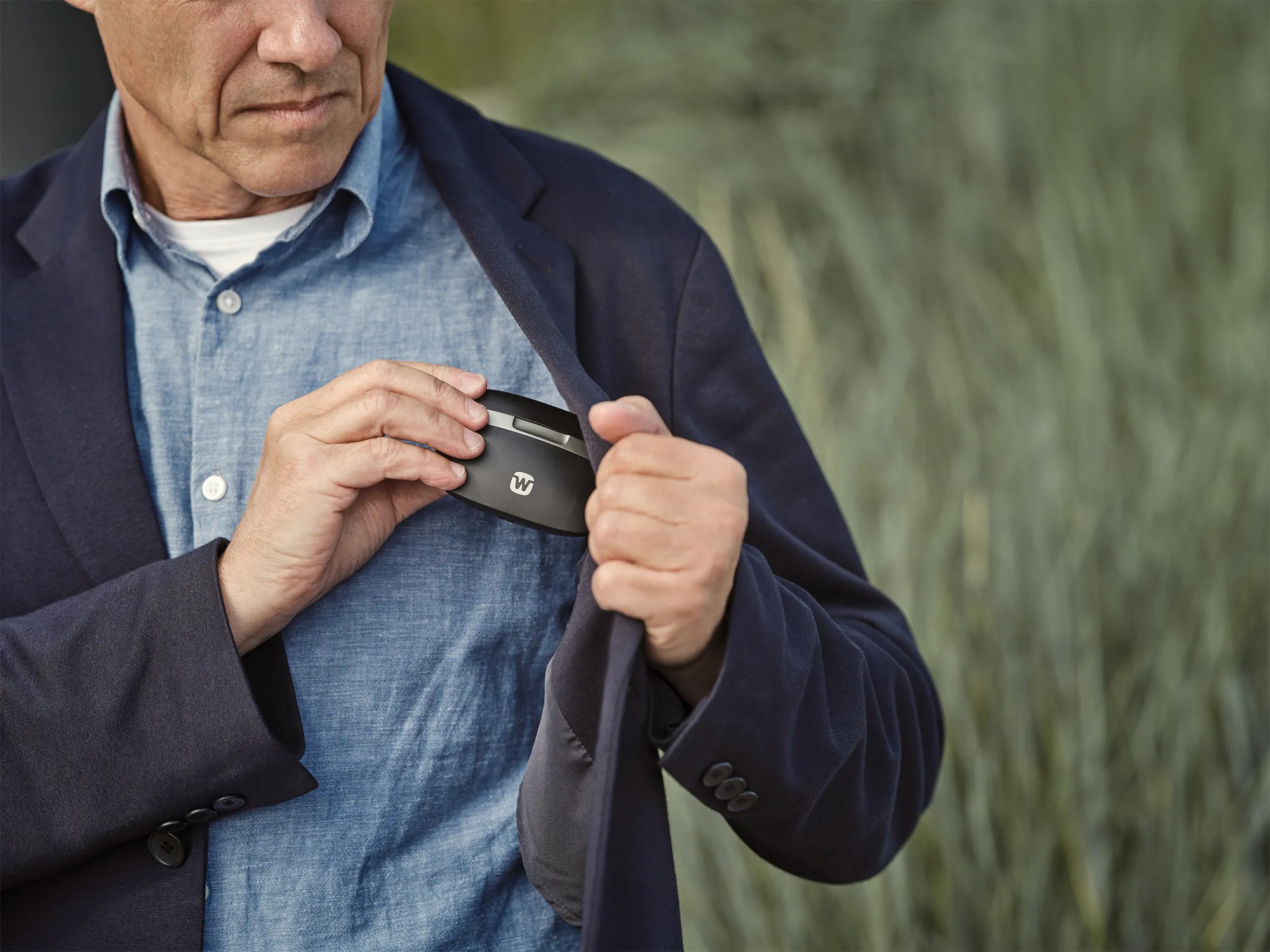 Man placing his Widex SmartRIC charger case in his pocket charging hearing aids on the go.