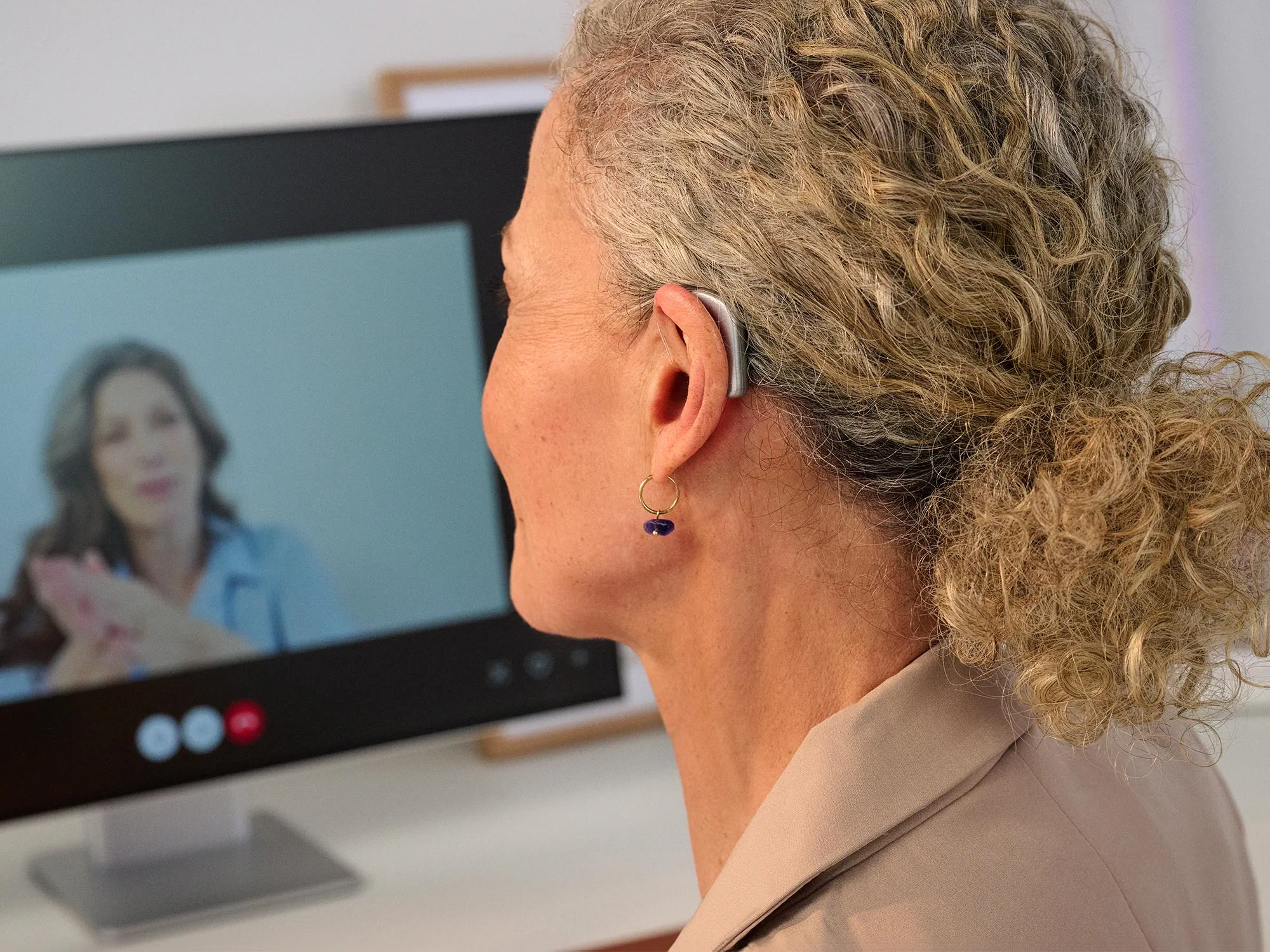 Mulher a trabalhar no computador, usando aparelhos auditivos Widex Smart RIC, mostrando como são discretos.