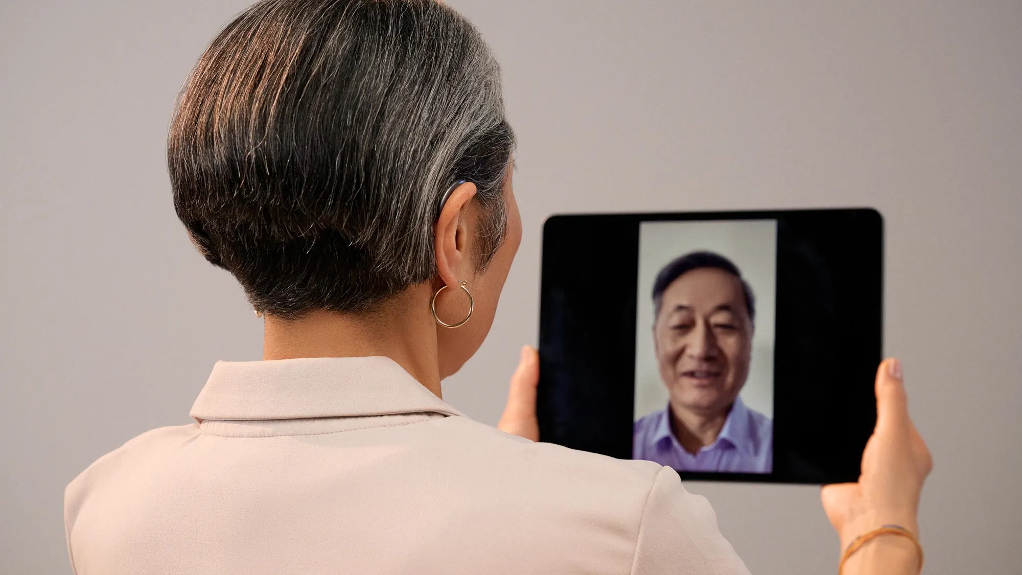 Person wearing hearing aid on Facetime with friend