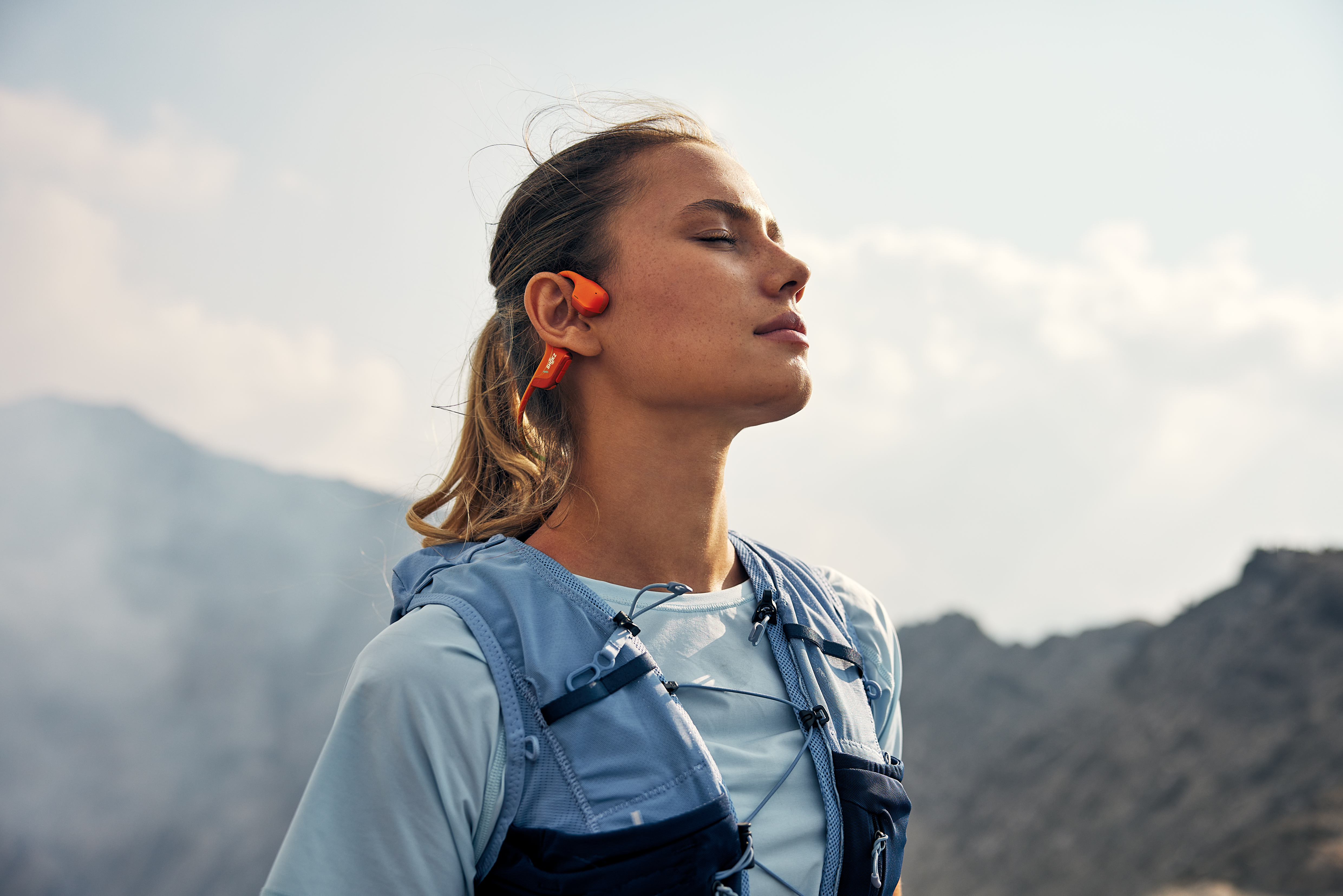 Mulher a utilizar auriculares open ear Shokz enquanto corre
