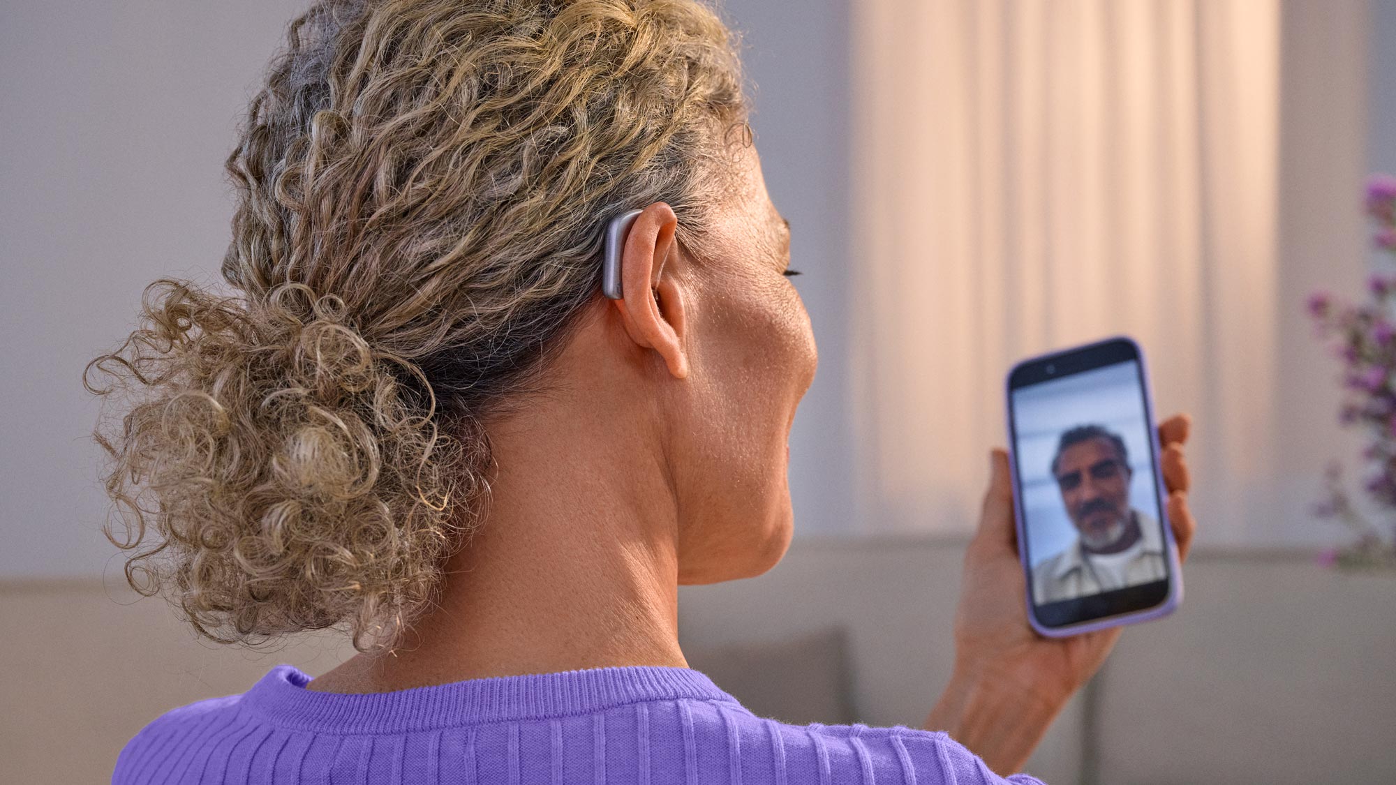 Mulher a fazer videochamada com os aparelhos auditivos colocados